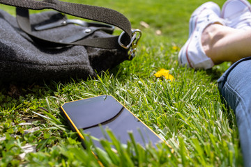 Person sitting on the grass with smartphone and relaxing