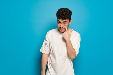 Young man over blue background looking to the front