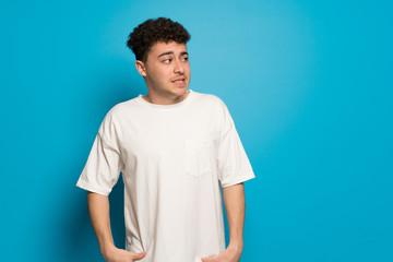 Young man over blue background is a little bit nervous and scared pressing the teeth