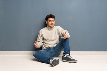 Young man sitting on the floor having doubts