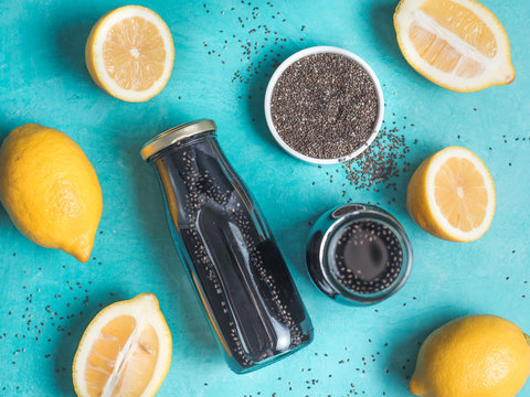 Detox activated charcoal black chia water or lemonade with lemon on bright blue background. Two bottle with black chia infused water. Detox drink idea and recipe. Vegan food and drink. Top view.
