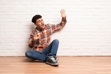 Young man sitting on the floor nervous and scared
