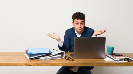 Business man in a office having doubts while raising hands