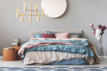 Golden chandelier above kind size with beige, blue and pastel pink bedding
