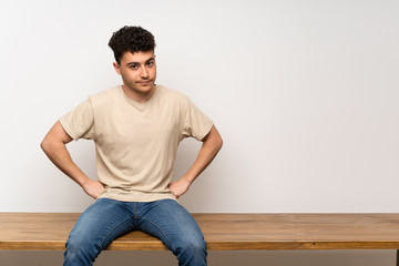Young man sitting on table angry