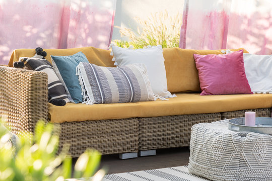 Real photo of colorful pillows on a rattan sofa on the terrace