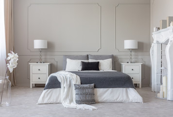 King size bed with grey and white sheets between two wooden bedside tables with stylish new york's...