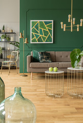 Elegant green and gold living room with comfortable brown sofa, coffee tables and golden chandelier