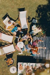 Top view on friends relaxing next to sunbeds during grill party in the garden