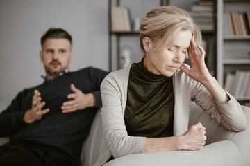 Depressed and tired wife with a headache in the middle of a conflict with a jealous husband - obrazy, fototapety, plakaty
