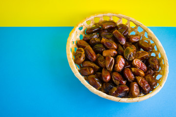 Dried dates on a yellow blue background. Holy month of Ramadan, concept. Righteous Muslim lifestyle. Starvation. Dates in a wooden basket in the style of minimalism