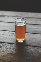 Half pint glass of craft beer on a pub bench.