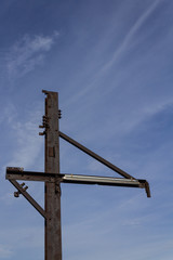Metal stanchion with heavy rusted patina against a blue sky with light clouds, vertical aspect