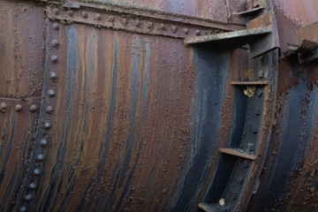 Riveted industrial metal pipe with rust patinas, copy space, horizontal aspect