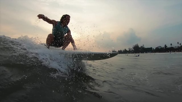 Young amateur surfer rides the wave during sunset at Weligama beach, Sri Lanka