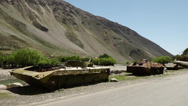 A steady, wide shot of neglected war tanks and solitude.