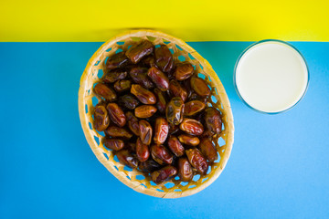 Dried dates and milk on a yellow blue background. Holy month of Ramadan, concept. Righteous Muslim lifestyle. Starvation. Dates in a wooden basket in the style of minimalism