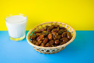 Dried dates and milk on a yellow blue background. Holy month of Ramadan, concept. Righteous Muslim lifestyle. Starvation. Dates in a wooden basket in the style of minimalism