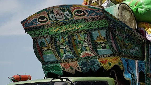 A steady, low angle, close up shot of a vivid, symbolic painting over the top of a truck. 