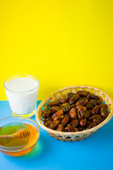 Dried dates, milk and honey on a yellow blue background. Holy month of Ramadan, concept. Righteous Muslim lifestyle. Starvation. Dates in a wooden basket in the style of minimalism