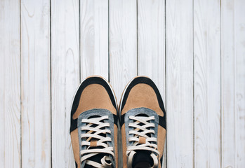 A pair of suede sneakers on a rustic wooden background. The concept of jog and sports shoes. Top view, copy space.