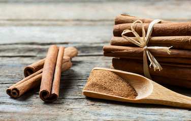 Close up cinnamon sticks and cinnamon powder in wooden spoon  on wooden table background,  healthy...