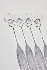 Row of four wine glasses. Abstract shadows, sunlight, white background.