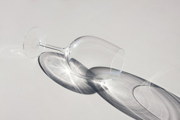Fototapeta na wymiar Wine glass lying on the table. Abstract shadows, sunlight.