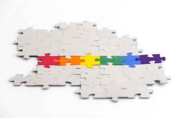 LGBT pride flag, built from a puzzle, among gray puzzles, short focus, on a white background, side view