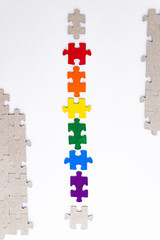 LGBT pride flag, built from a puzzle, among gray puzzles, short focus, on a white background, top view