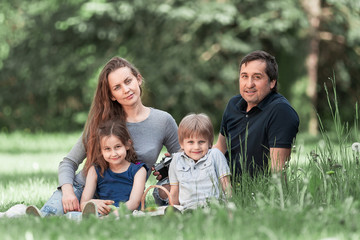 Fototapeta premium parents with small two children on the lawn on a spring day