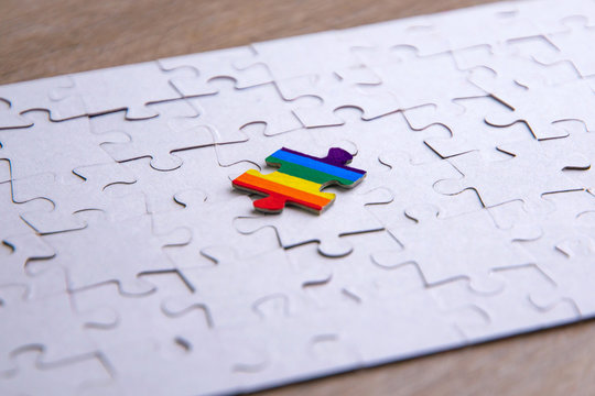 Place of LGBT people in the public structure: puzzle with the coloring of the rainbow flag against a white mosaic, front view