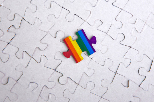 Place of LGBT people in the public structure: puzzle with the coloring of the rainbow flag against a white mosaic, front view