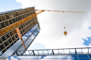 construction of buildings: the lifting crane bears a bucket with concrete, against a background of blue sky, the view from below