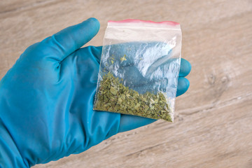 sachet of synthetic smoking substance, cannabis, weed, marijuana on the palm of a laboratory researcher