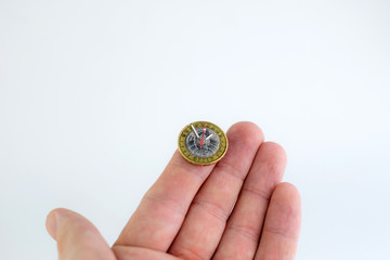 time and money, concept: second, hour and minute hands on a coin of 2 Belarusian rubles, on a person’s hand