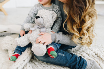 Beautiful young mother holding her son and a teddy bear