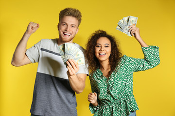 Young couple with money on color background