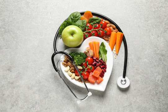 Flat lay composition with plate of products for heart-healthy diet on grey background