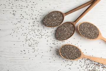 Spoons with chia seeds on wooden background, flat lay. Space for text