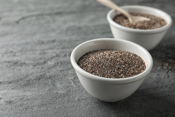 Bowl with chia seeds on grey background, space for text