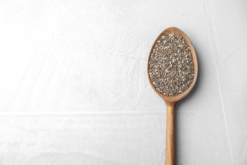 Spoon with chia seeds on light background, top view. Space for text