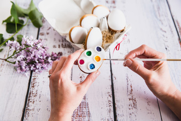 Hand decorating gingerbread colorful cookies on wooden background. Top View