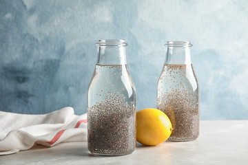 Composition with bottles of water and chia seeds on table against color background