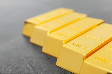 Shiny gold bars on grey background, closeup