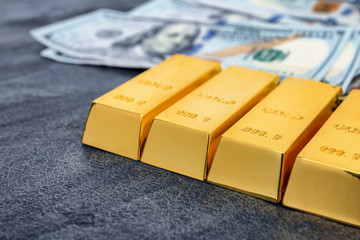 Gold bars and dollar bills on table, closeup