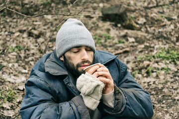 Poor homeless man with cup in city park