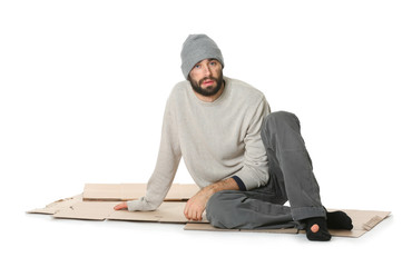 Poor homeless man sitting on cardboard, white background