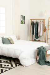 Wooden rack with clothes in modern bedroom interior