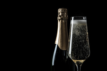 Bottle and glass of champagne on black background, space for text